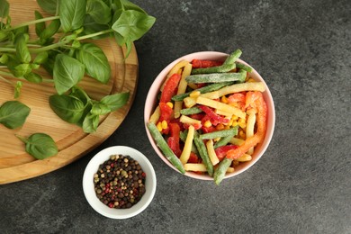 Different frozen vegetables, spices and fresh basil on grey table, flat lay