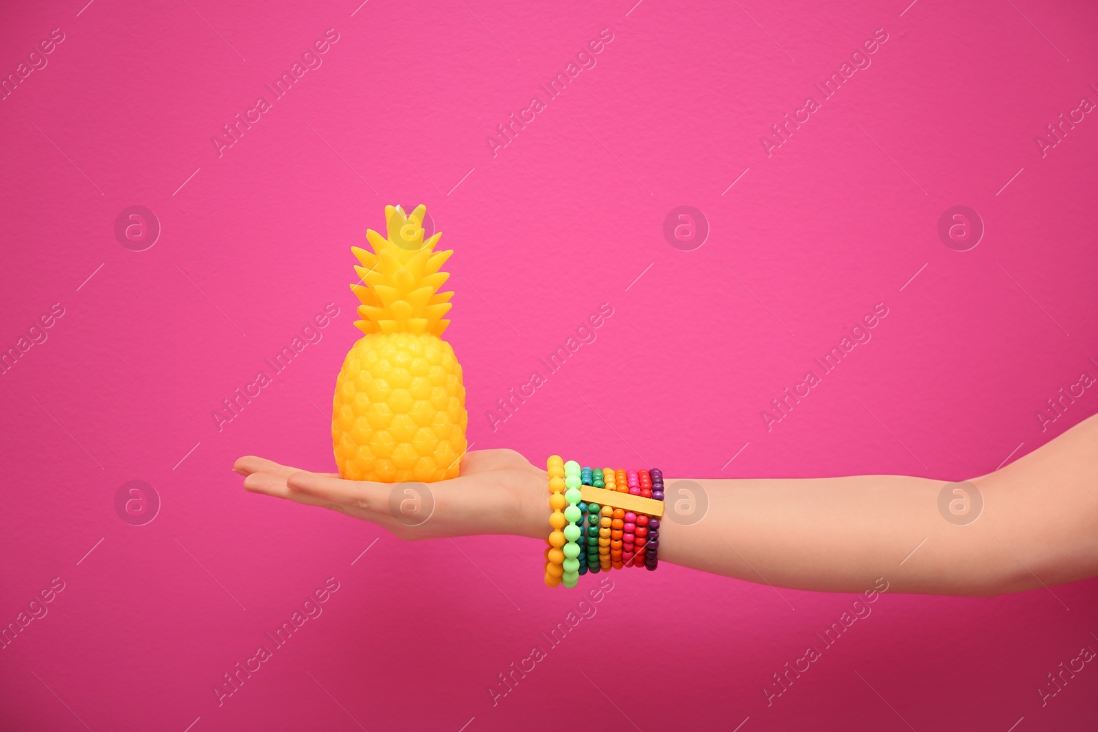 Photo of Woman holding stylish pineapple candle on color background