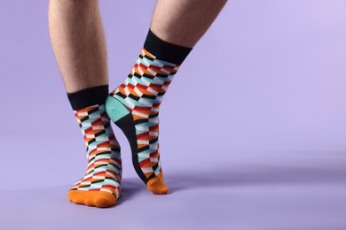 Man in stylish colorful socks on violet background, closeup. Space for text