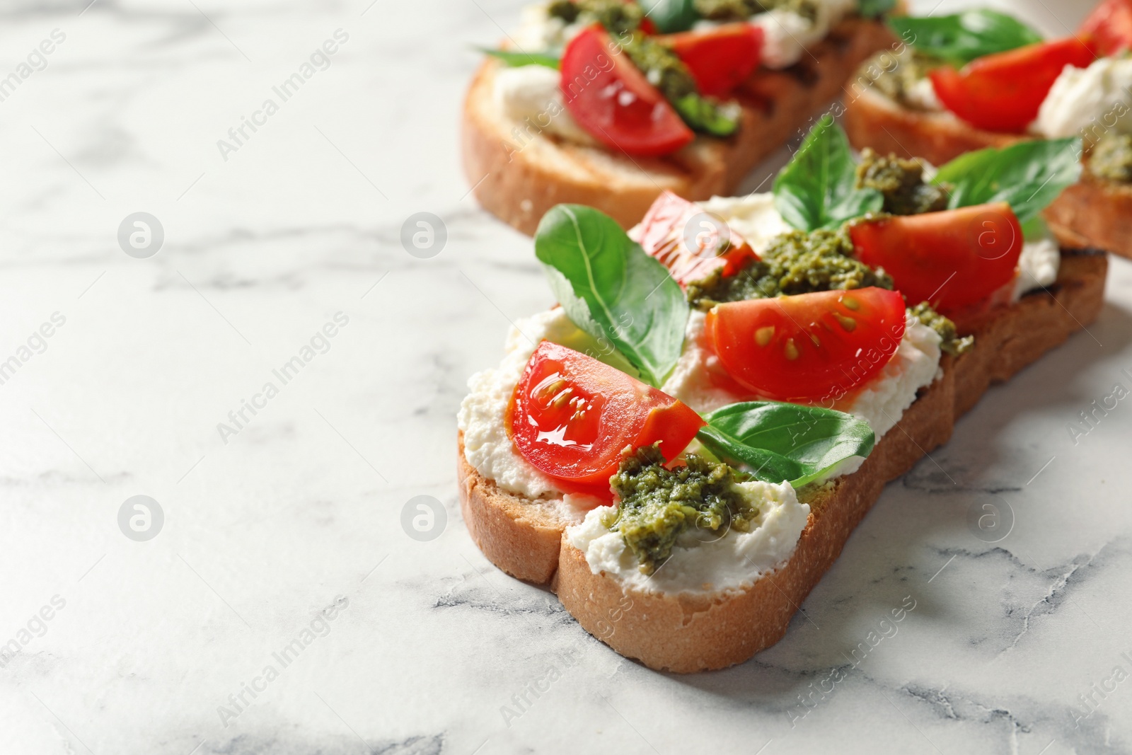 Photo of Toasted bread with tasty cream cheese and tomatoes on marble table. Space for text