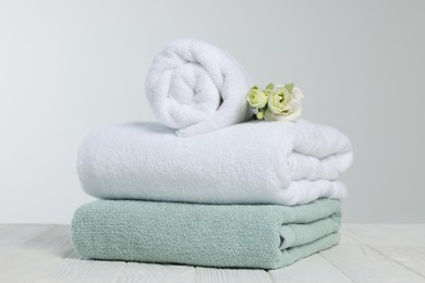 Photo of Soft towels with flowers on wooden table against white background