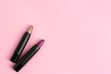 Bright lipsticks in black tubes on pink background, flat lay. Space for text