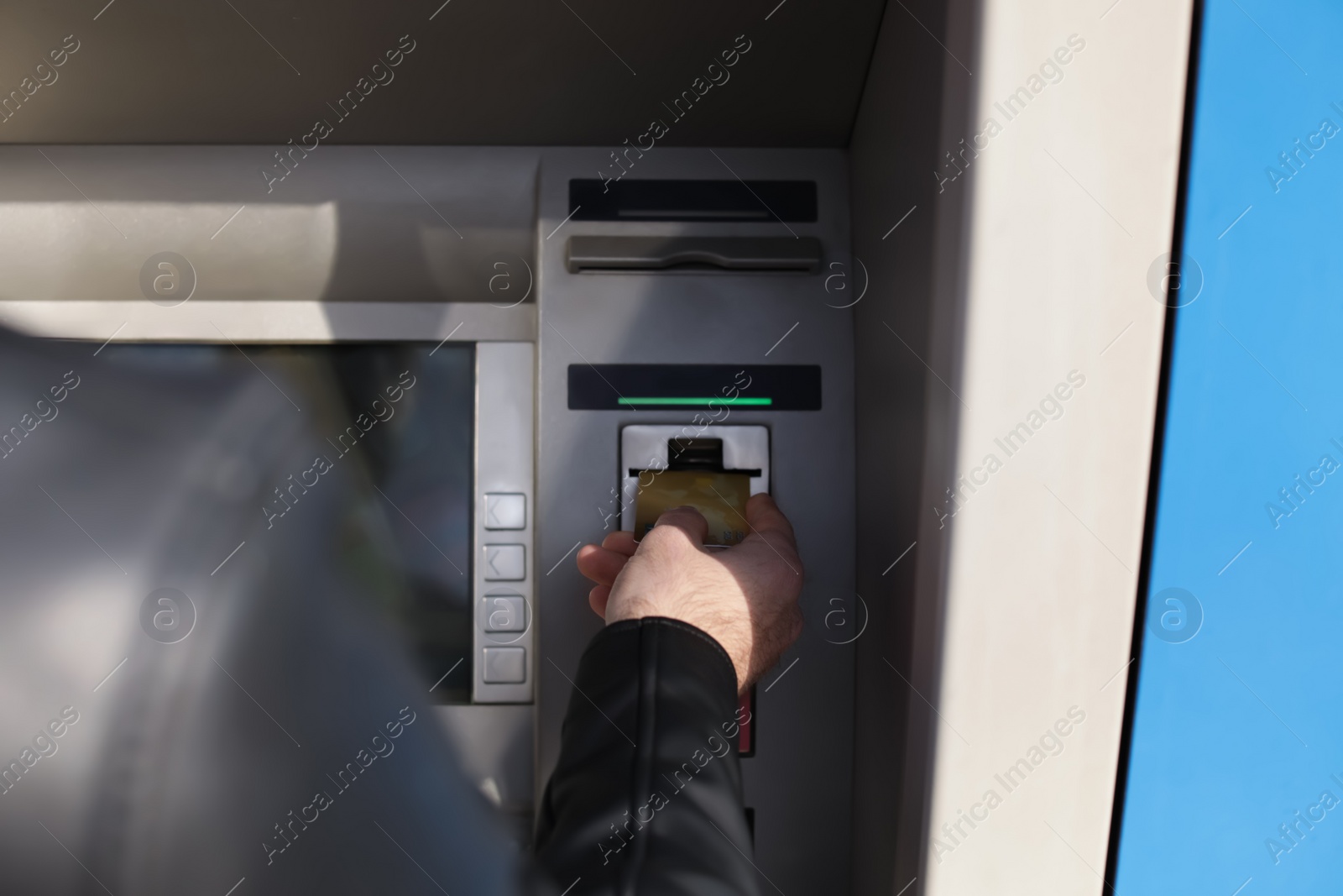 Photo of Man inserting credit card into cash machine outdoors, closeup