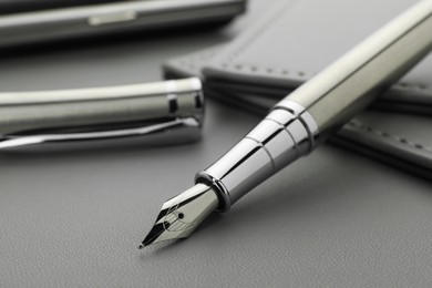 Photo of Stylish silver fountain pen on grey textured table, closeup