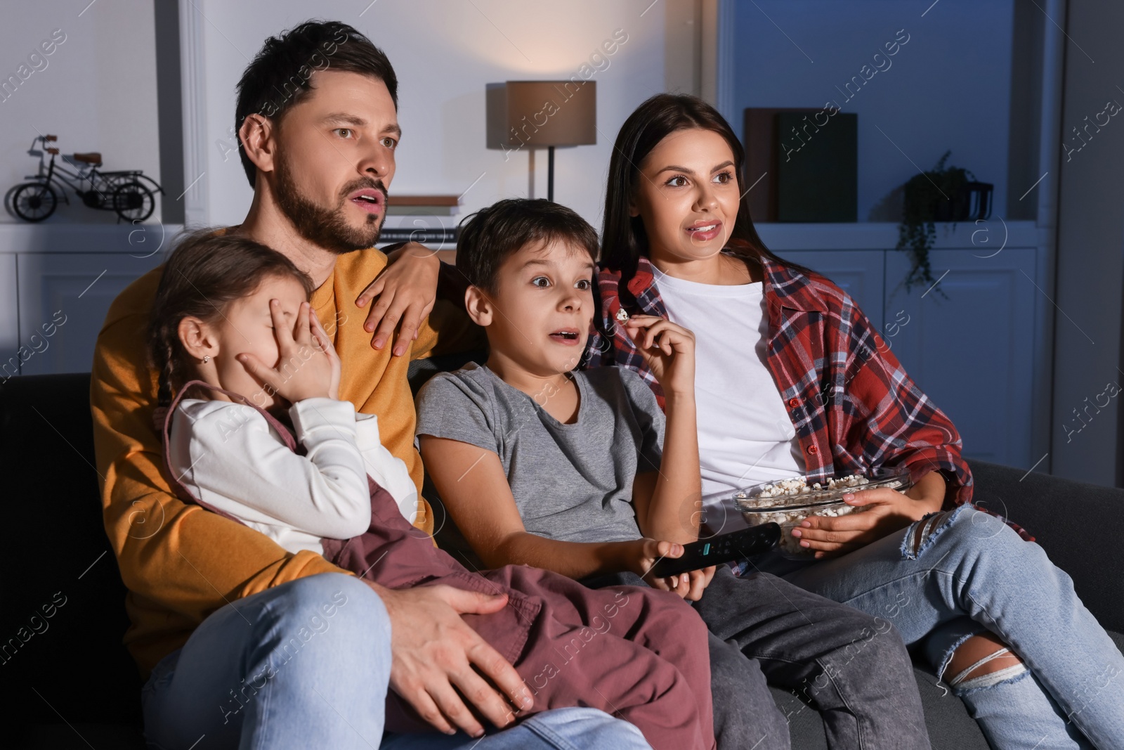 Photo of Emotional family watching TV at home in evening