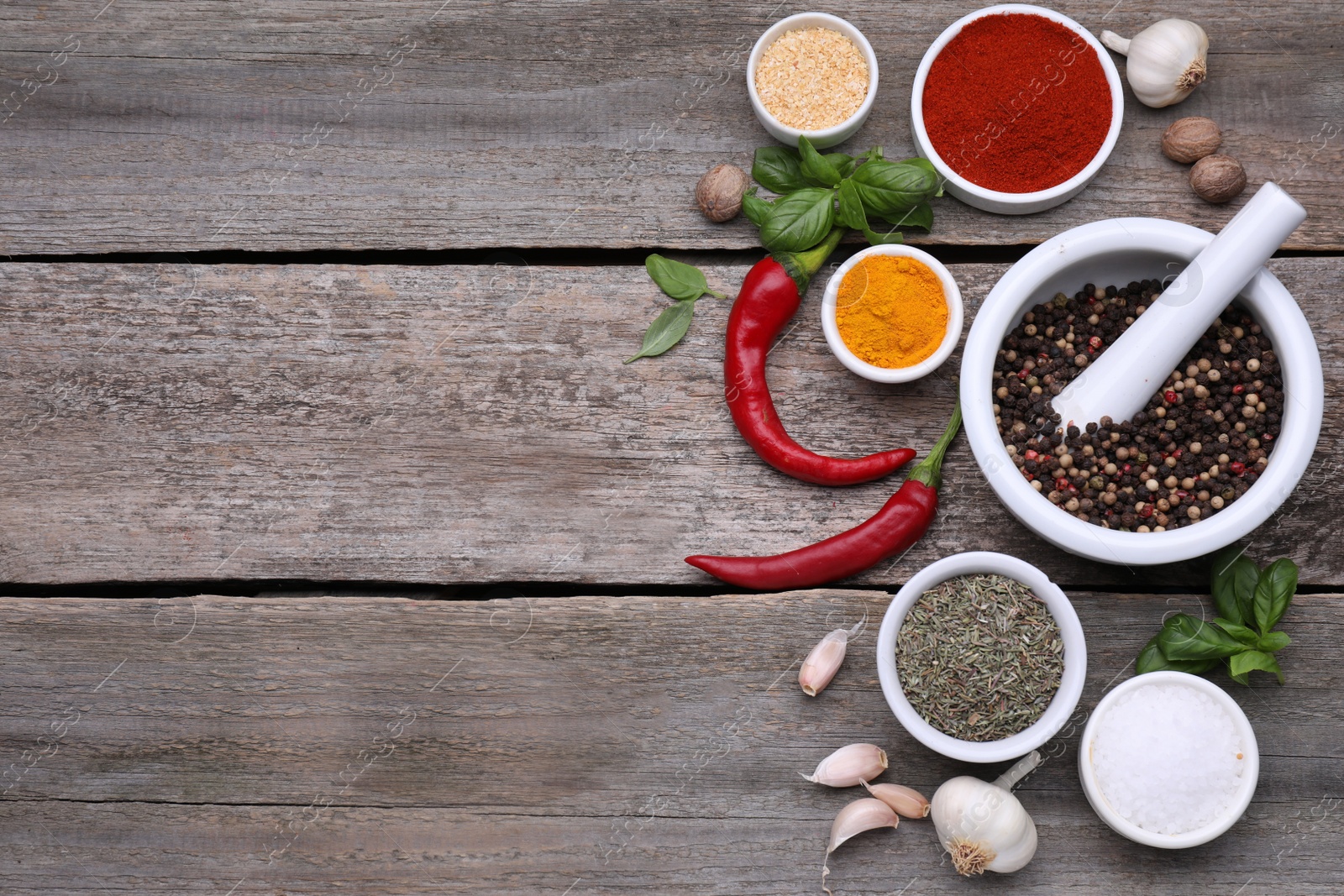 Photo of Mortar with pestle and different spices on wooden table, flat lay. Space for text