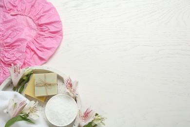 Photo of Flat lay composition with shower cap and toiletries on white wooden background. Space for text