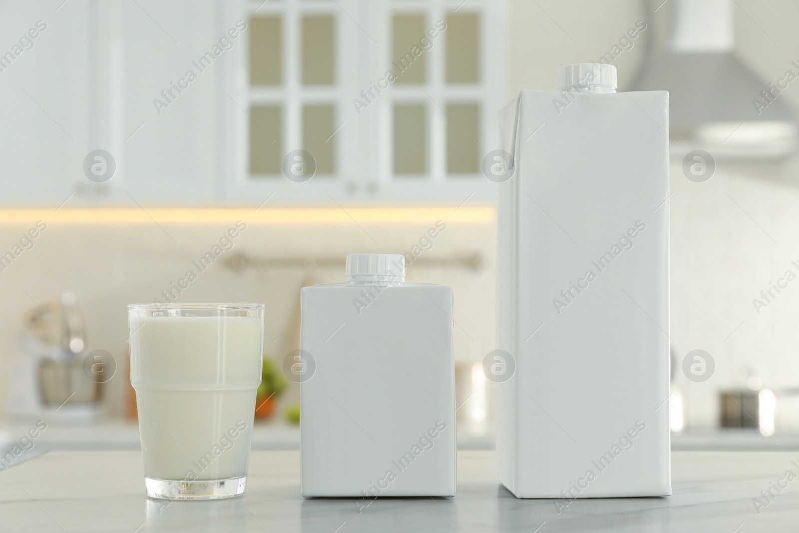 Photo of Carton boxes and glass of milk on table in kitchen