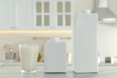 Carton boxes and glass of milk on table in kitchen