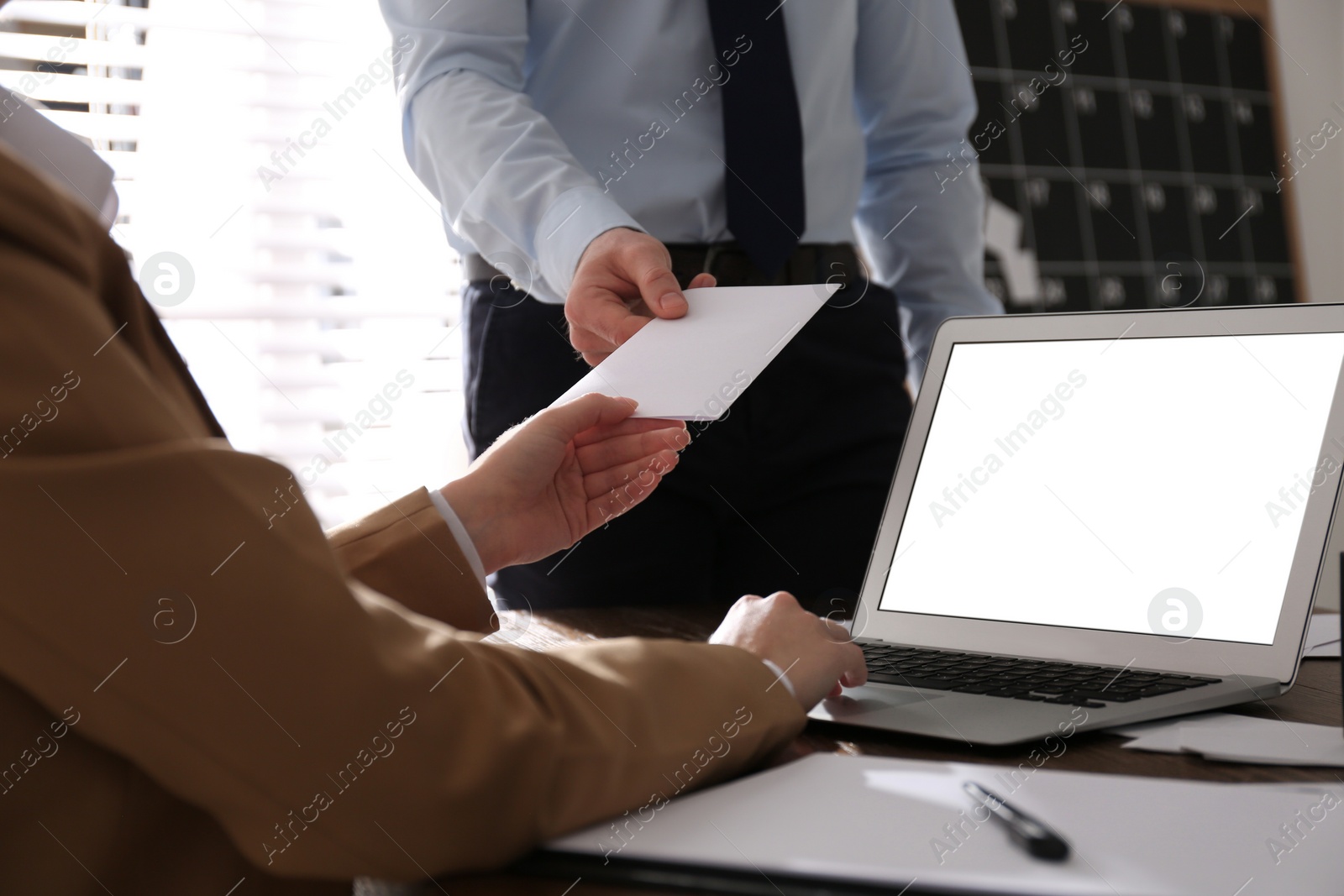 Photo of Employee giving resignation letter to boss in office, closeup