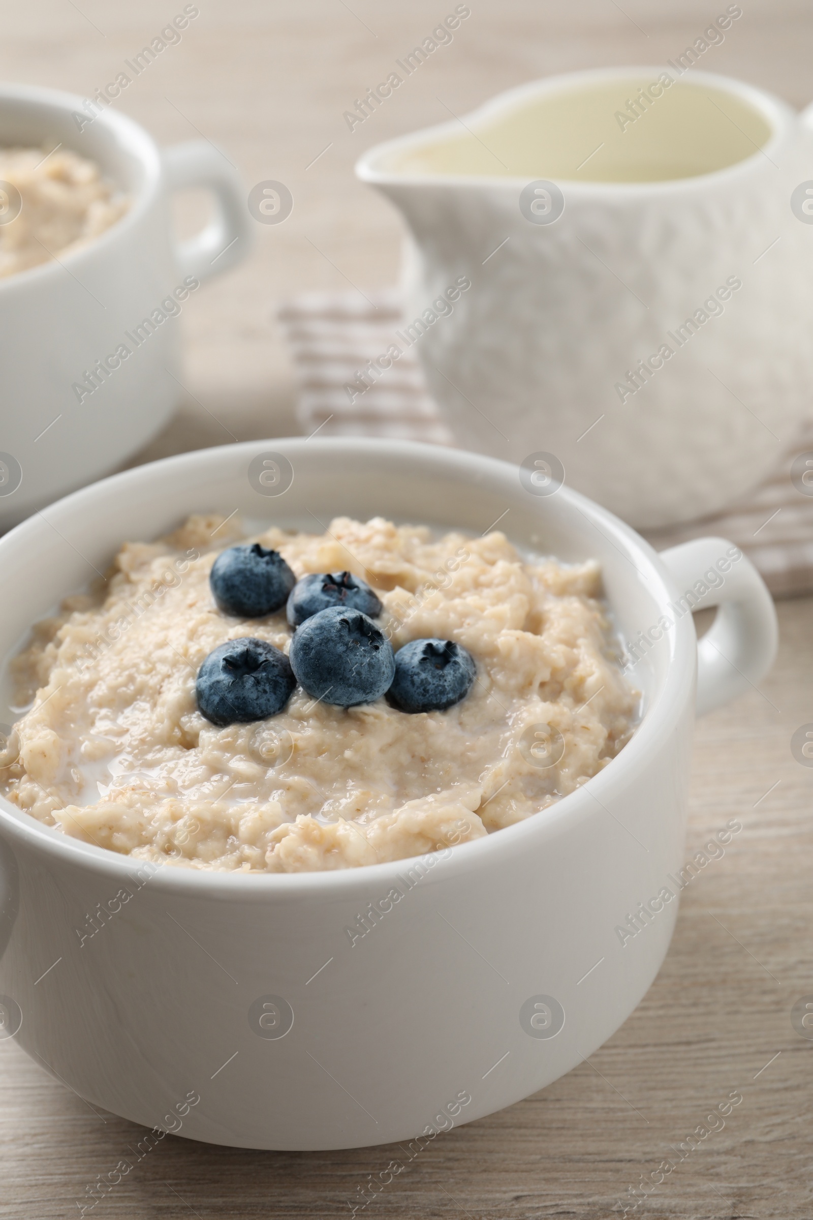 Photo of Tasty oatmeal porridge with blueberries in bowl served on wooden table