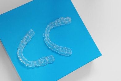 Transparent dental aligners on beige background, top view. Space for text