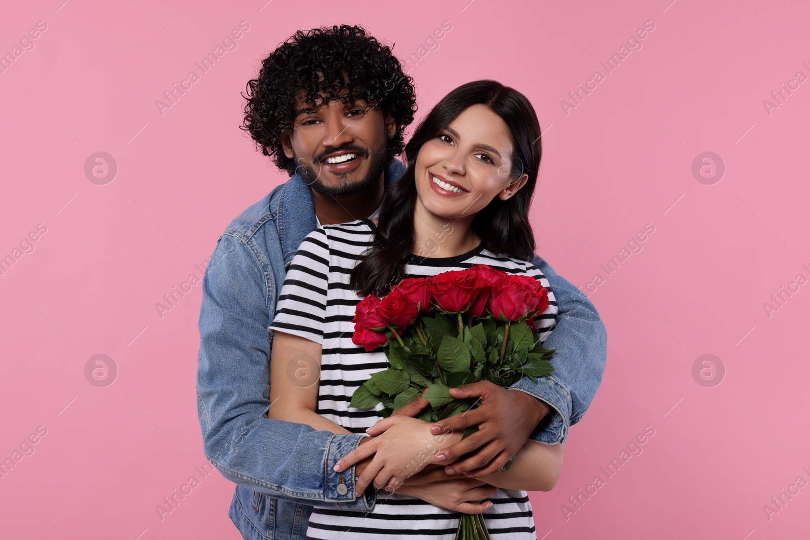 Photo of International dating. Happy couple with bouquet of roses on pink background