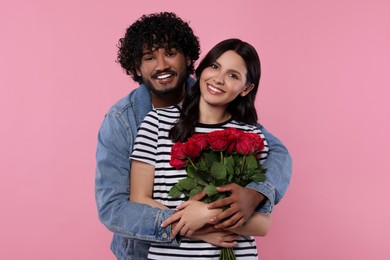 Photo of International dating. Happy couple with bouquet of roses on pink background