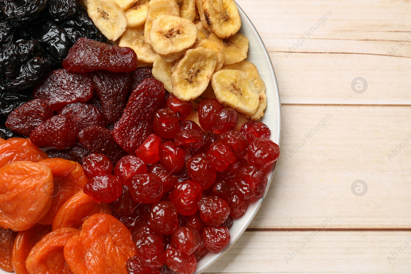 Photo of Delicious dried fruits on white wooden table, top view. Space for text