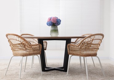 Photo of Table, chairs and vase of hydrangea flowers in dining room. Stylish interior
