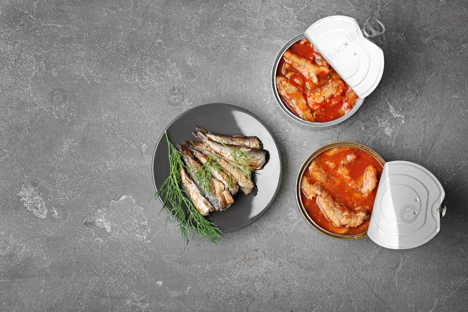 Photo of Flat lay composition with canned fish on grey background