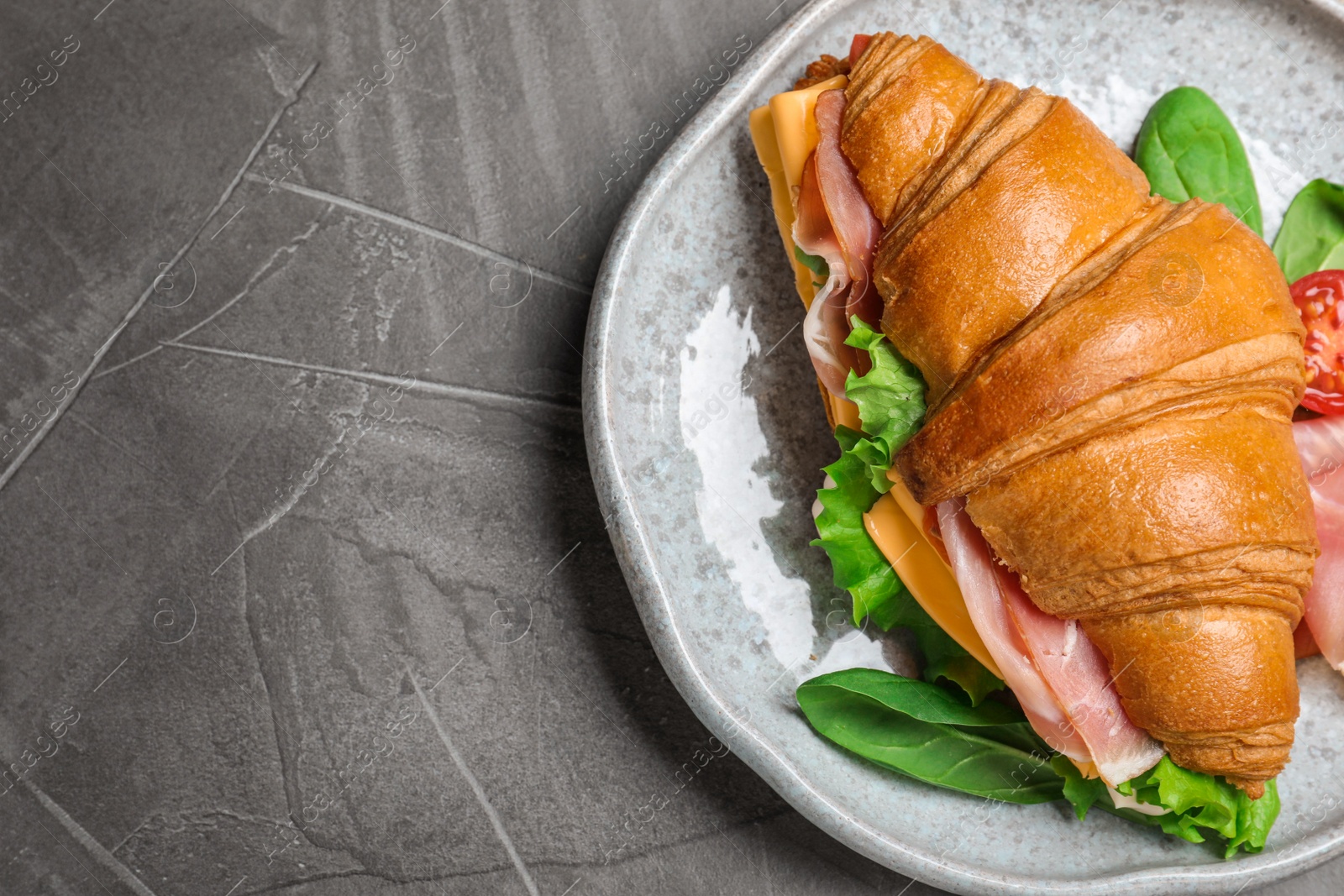 Photo of Tasty croissant sandwich with ham and cheese on grey table, top view. Space for text