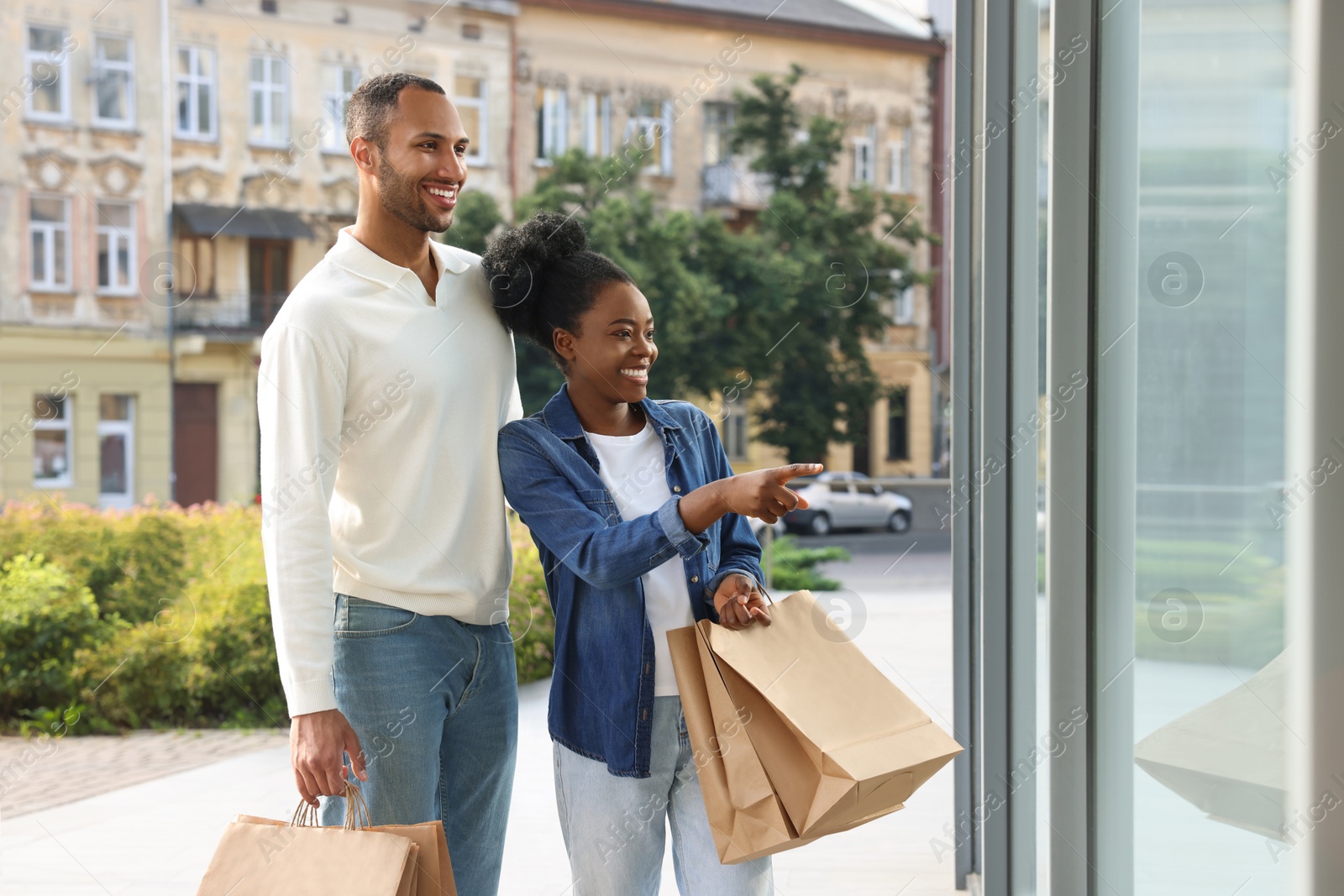 Photo of Family shopping. Happy couple with purchases near mall outdoors