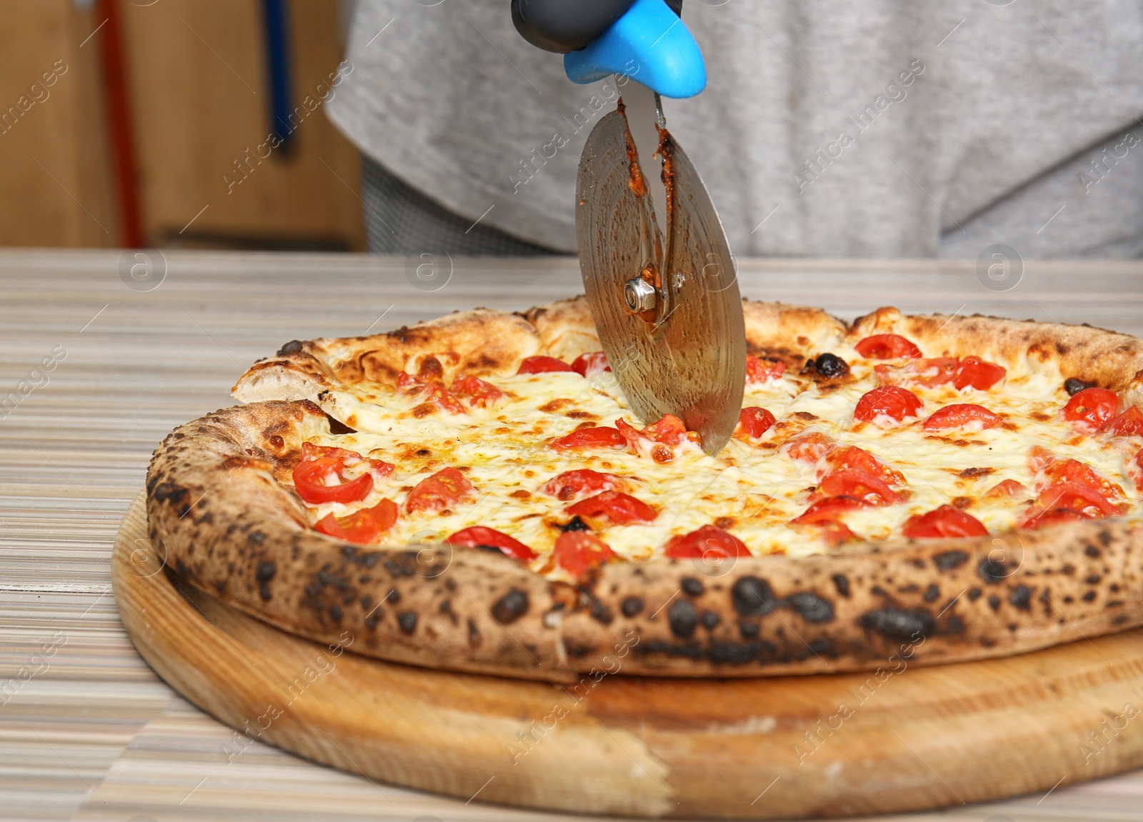 Photo of Professional chef cutting Italian oven baked pizza in restaurant, closeup