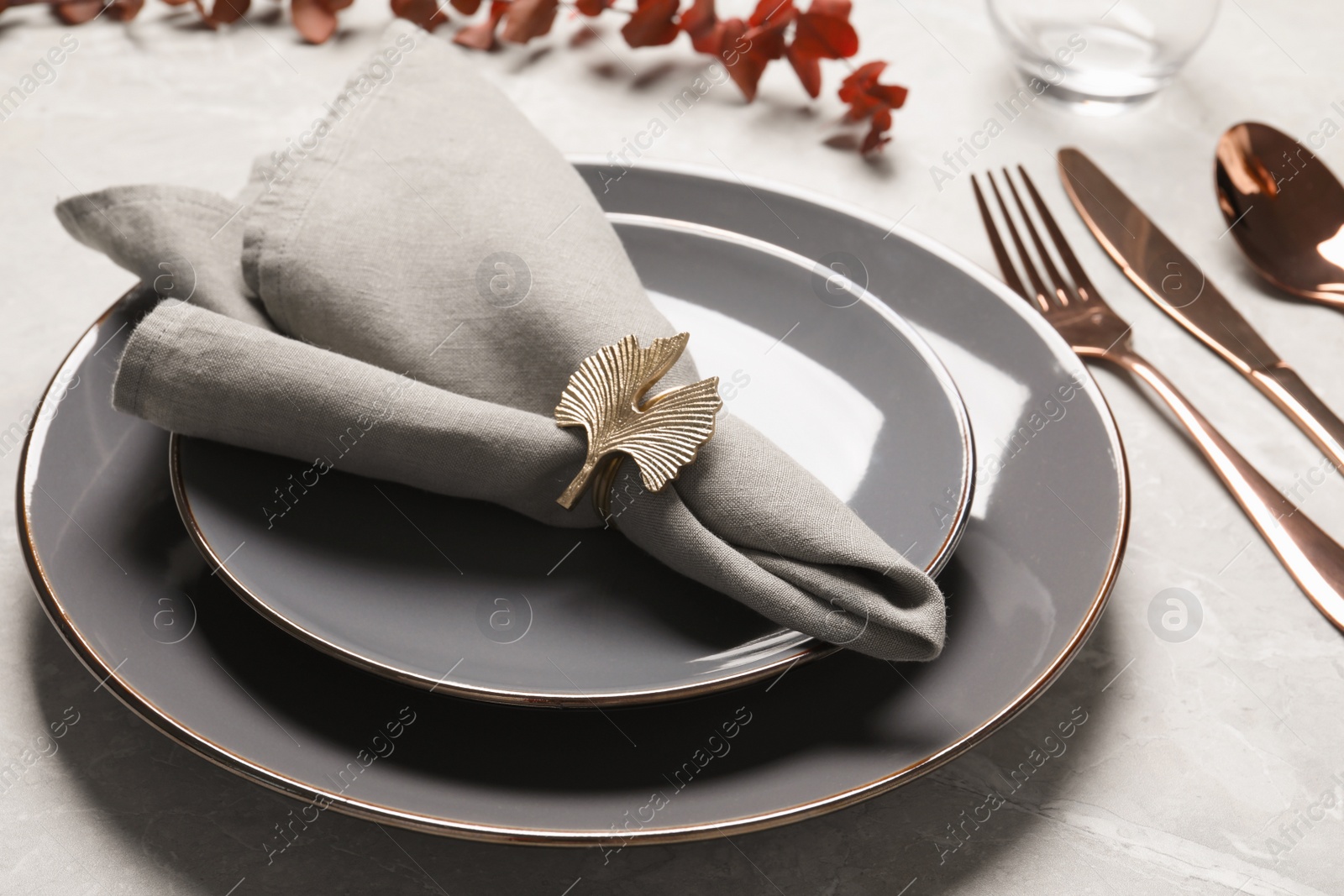 Photo of Plates with fabric napkin, decorative ring and cutlery on light gray marble table