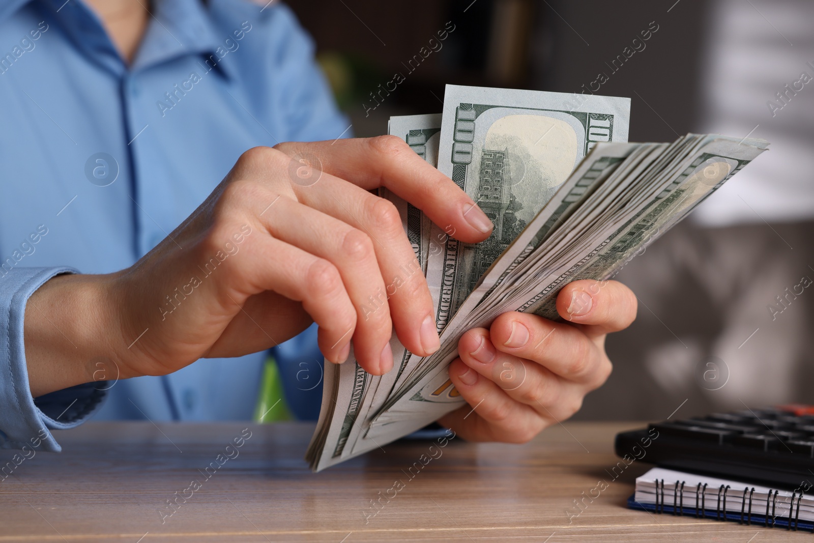 Photo of Money exchange. Woman counting dollar banknotes at wooden table, closeup