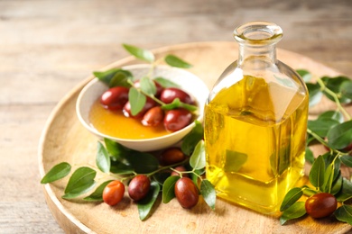 Photo of Glass bottle with jojoba oil and seeds on wooden table