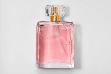 Photo of Pink women's perfume in bottle on white background, top view