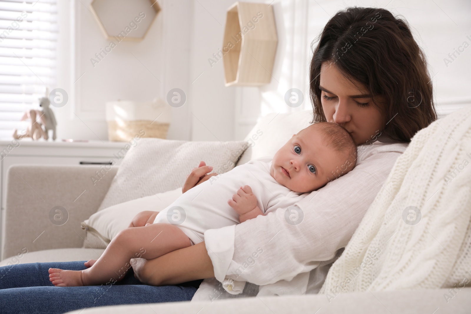 Photo of Young mother with her cute baby on sofa at home