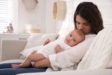 Young mother with her cute baby on sofa at home