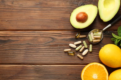 Photo of Different vitamin pills and fresh fruits on wooden table, flat lay. Space for text