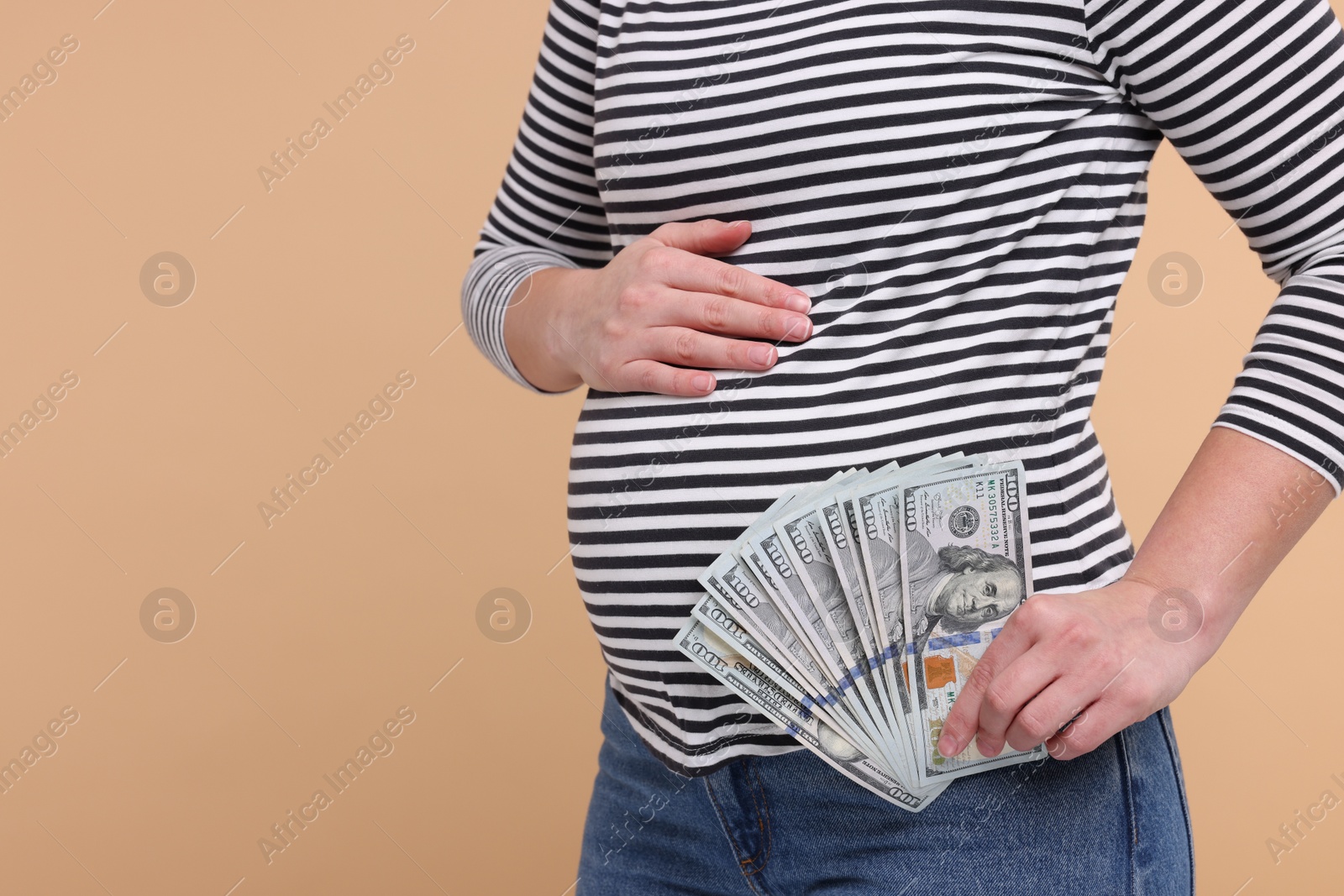 Photo of Surrogate mother. Pregnant woman with dollar banknotes on beige background, closeup. Space for text