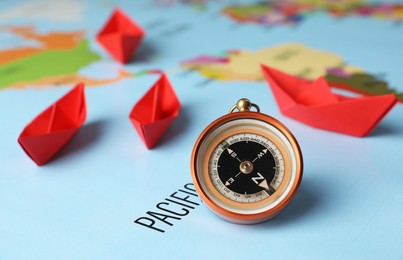 Photo of Bright paper boats and compass on world map
