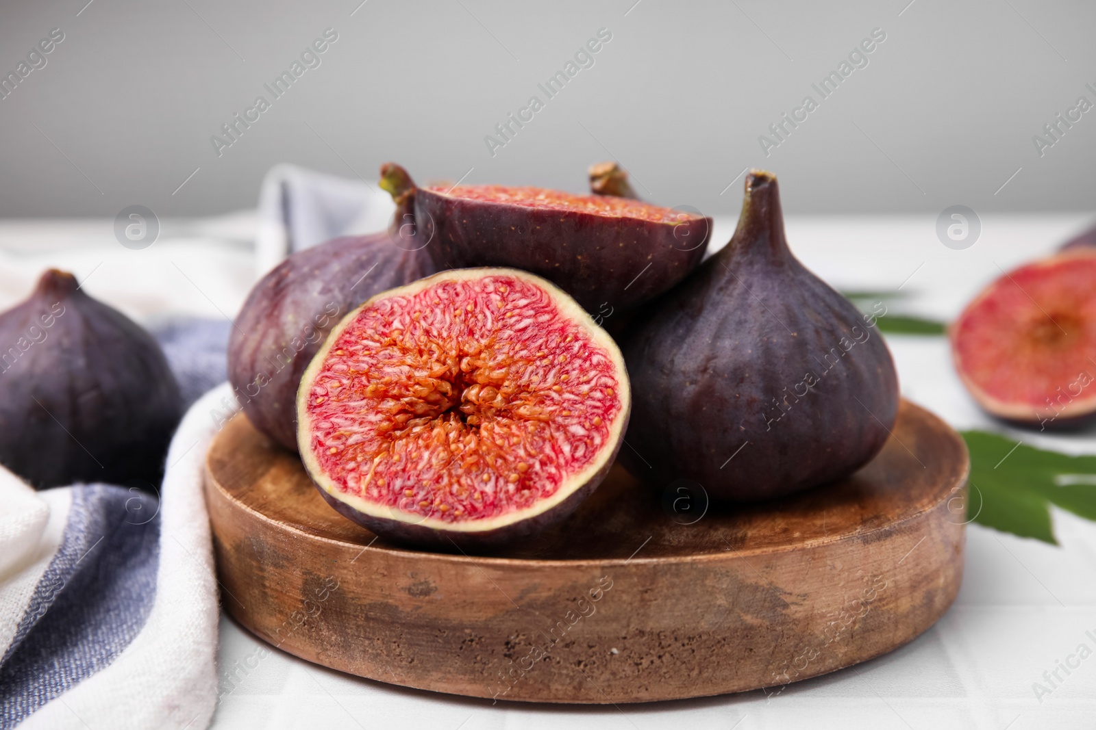 Photo of Fresh ripe purple figs on white tiled table