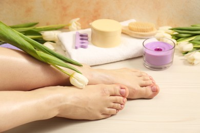 Photo of Woman with neat toenails after pedicure procedure on wooden floor, closeup