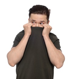 Embarrassed man covering face with t-shirt on white background