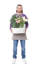 Male florist holding basket with flowers on white background