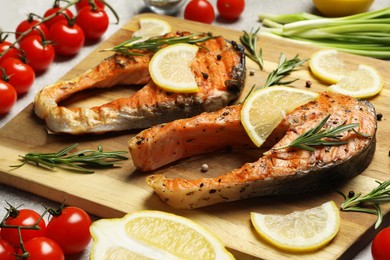 Photo of Tasty grilled salmon steaks and different ingredients on light grey table