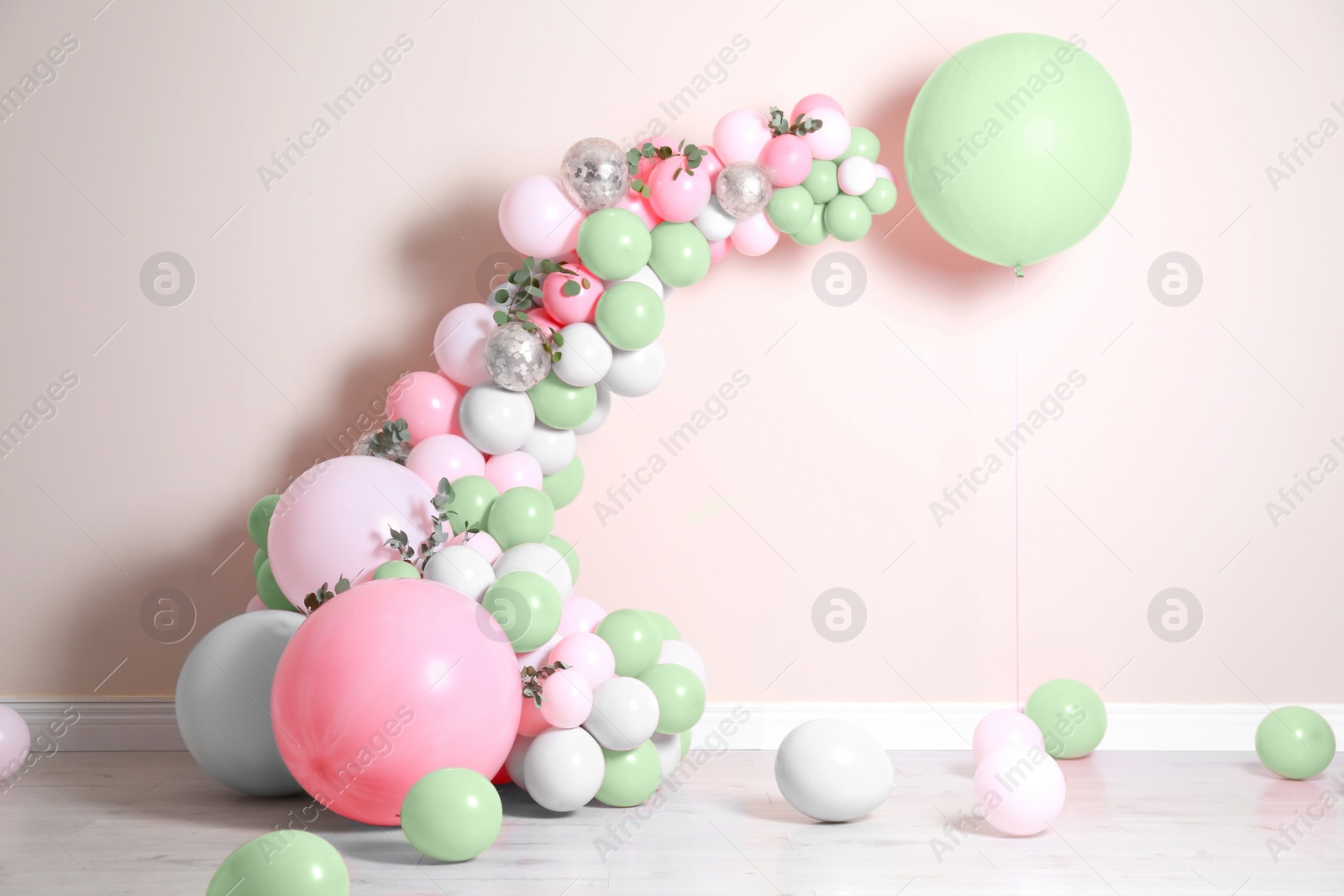 Image of Balloon garland near beige wall in room. Festive decor