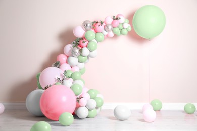 Balloon garland near beige wall in room. Festive decor