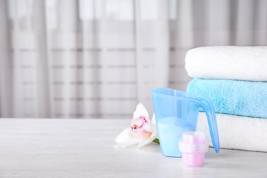 Composition with clean towels and laundry detergents on table against blurred background. Space for text