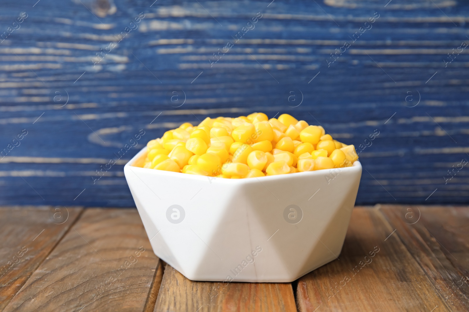 Photo of Bowl with corn kernels on wooden table