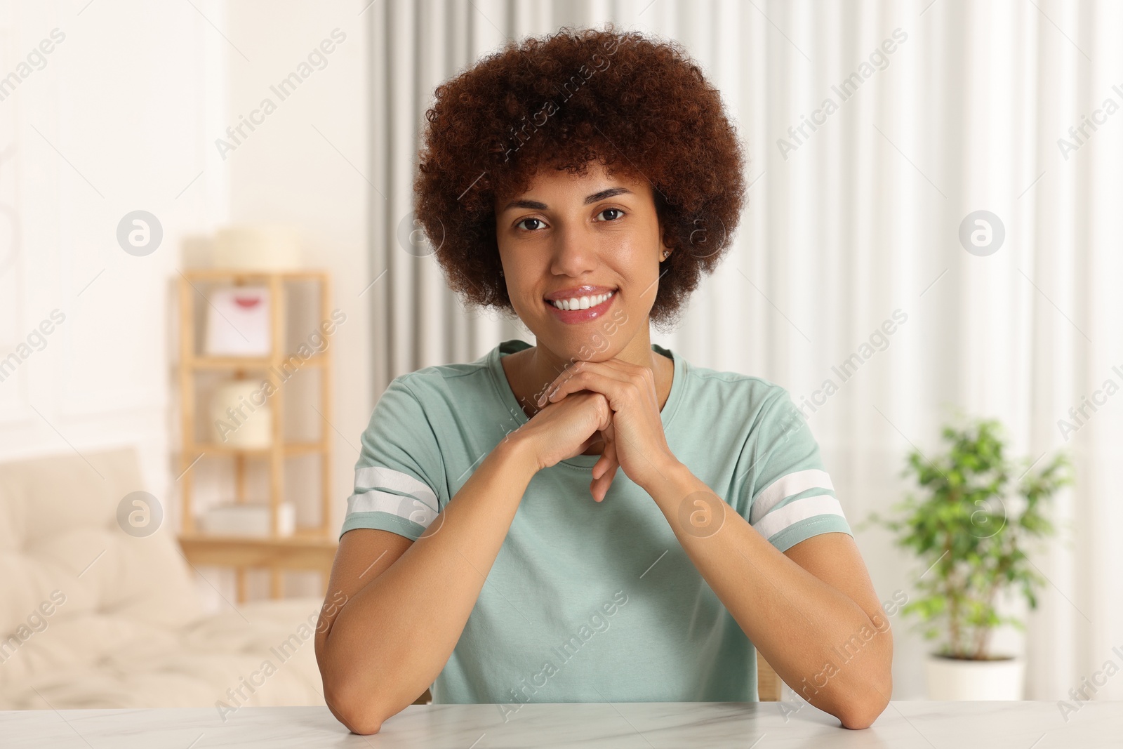 Photo of Happy young woman sitting at table in room