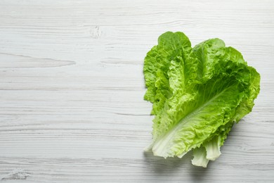 Photo of Fresh leaves of green romaine lettuce on white wooden table, top view. Space for text