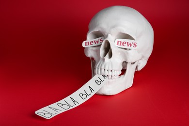 Information warfare concept. Saying useless nonsense as result of media propaganda influence. Human skull with paper cards on red background
