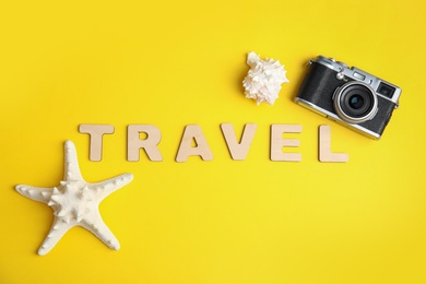 Flat lay composition with word TRAVEL and camera on color background. Tourist agency