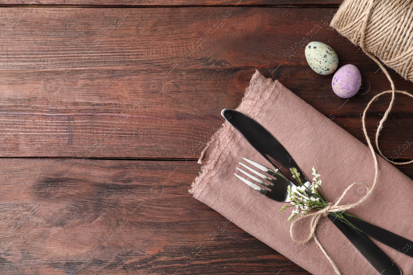 Photo of Cutlery set with quail eggs and space for text on wooden table, flat lay. Easter celebration