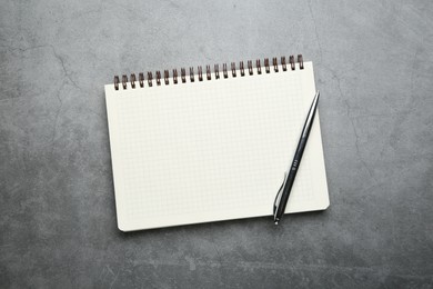 Photo of Notebook and pen on grey table, top view