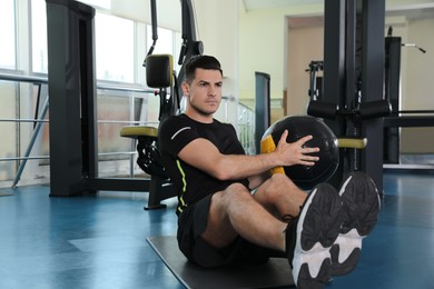 Photo of Athletic man exercising with medicine ball in modern gym