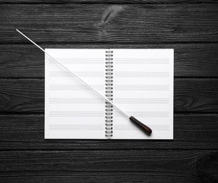 Photo of Conductor's baton and lead sheet on black wooden table, top view
